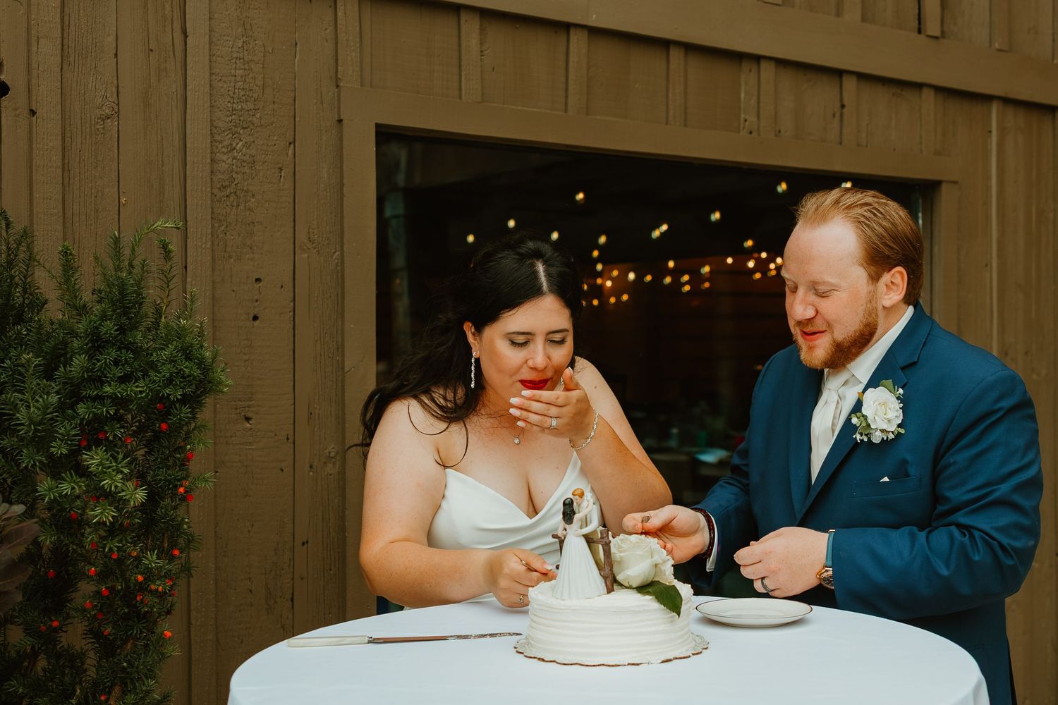 Bride laughing with hand over mouth after cake cutting at rustic outdoor wedding reception. Northwest Indiana wedding venues.