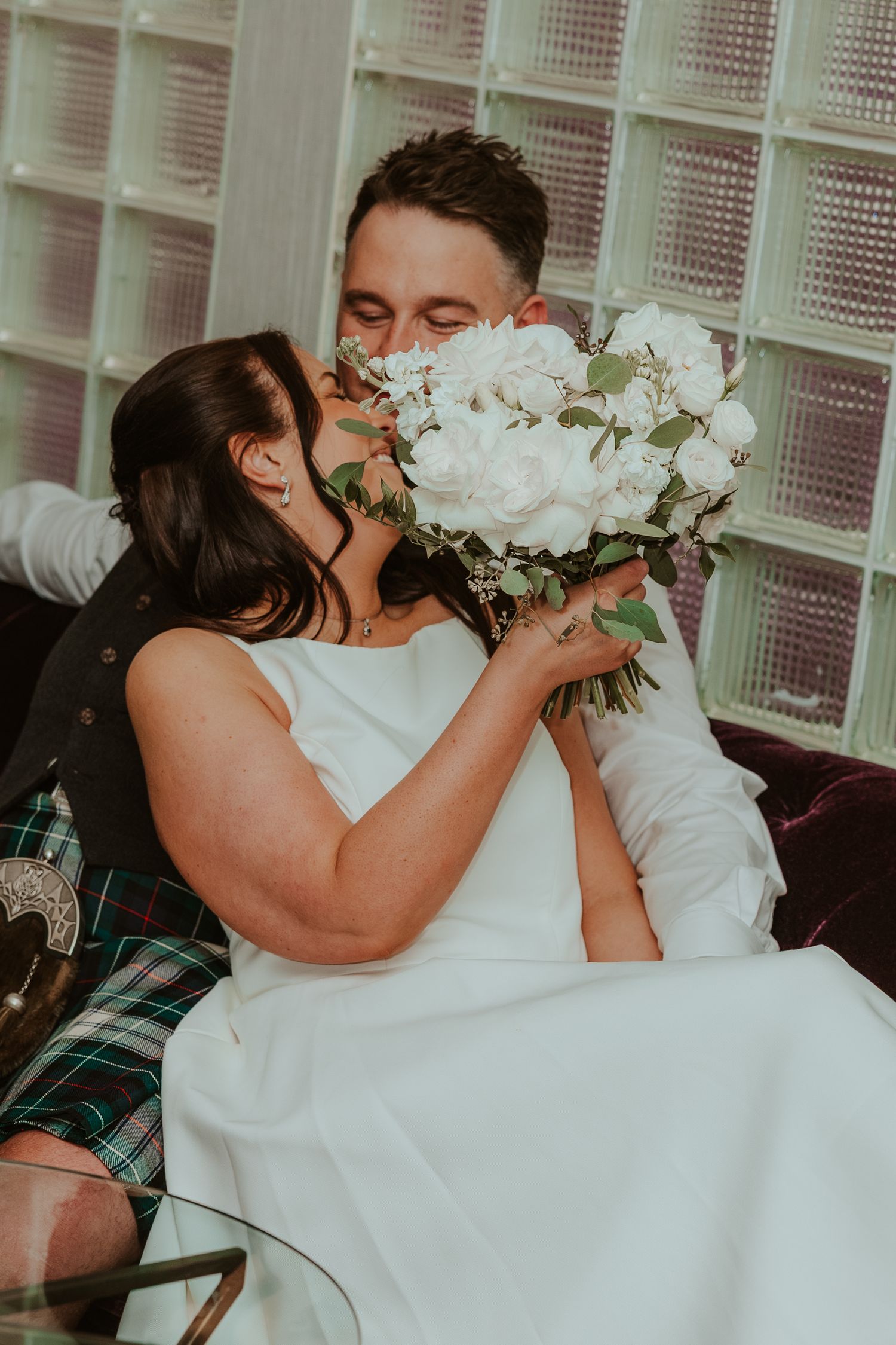 Bride and groom share a kiss hidden behind white peony bouquet. Chicago Thompson Hotel wedding.