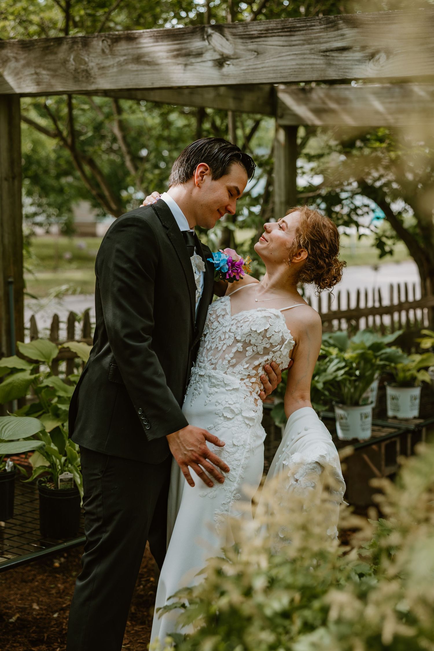 Wedding couple embraces tenderly in lush greenhouse garden setting. Chicagoland wedding venues.