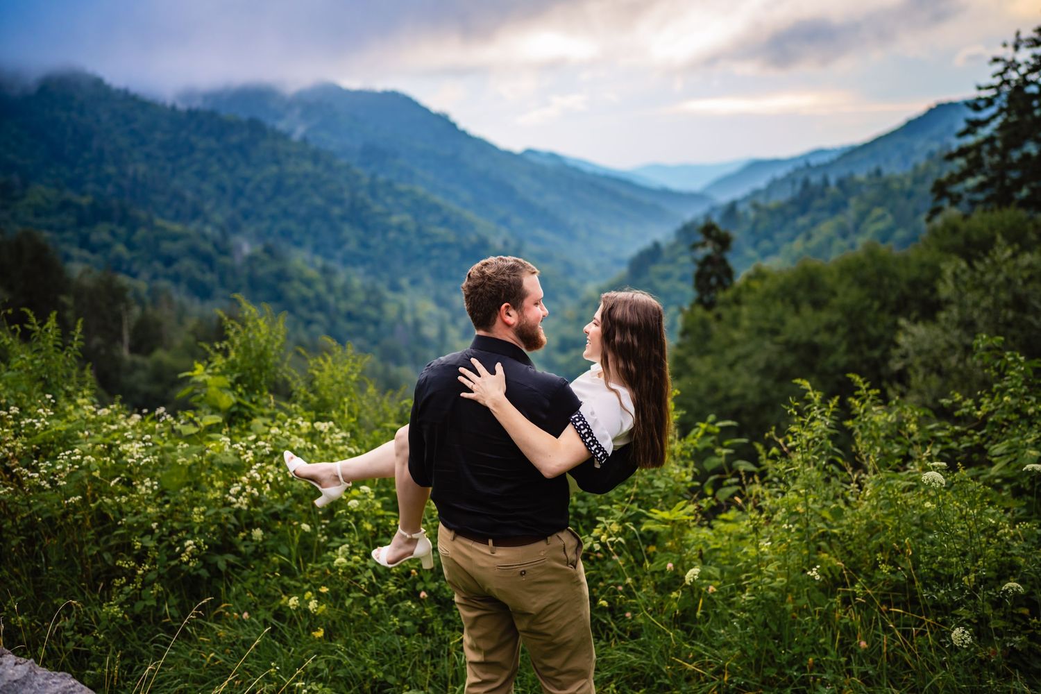 Couple embracing with breathtaking smoky mountain valley views behind them.