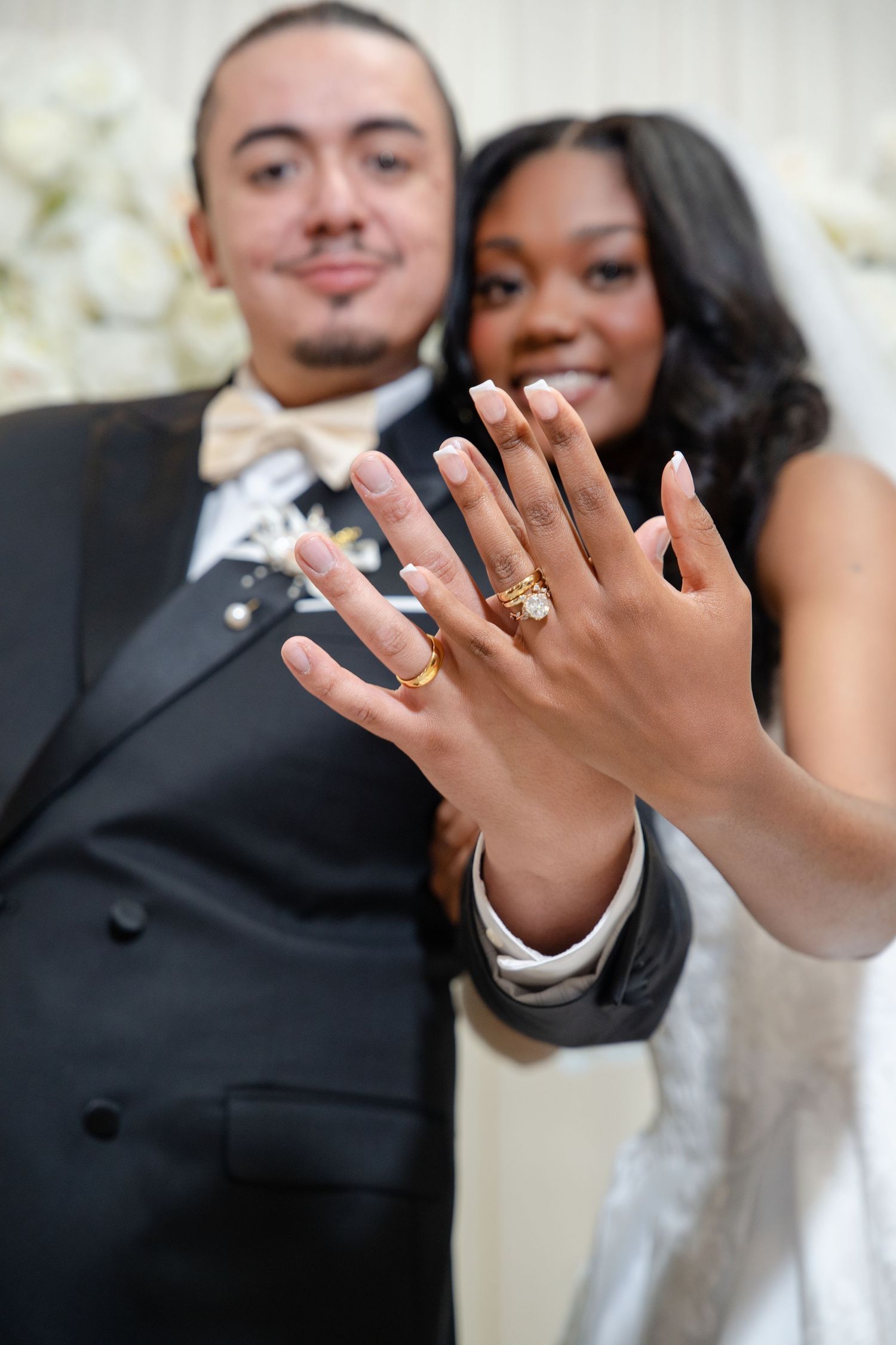 Newlywed couple smiling and showing off their gold wedding rings at their wedding ceremony.