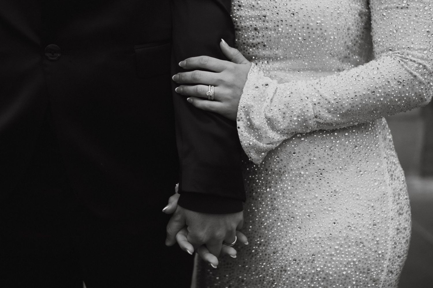 A pregnant woman in a sparkly sequin dress poses against a dark background, showing off her baby bump.