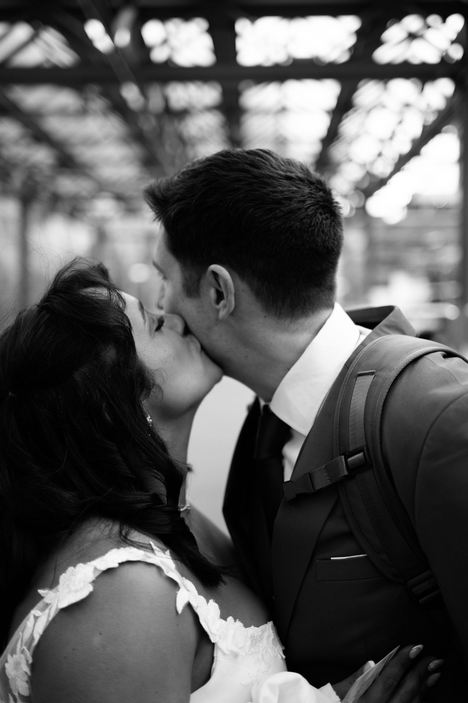 Bride and groom sharing a passionate kiss outdoors under a pergola in a black and white wedding photo in Switzerland.