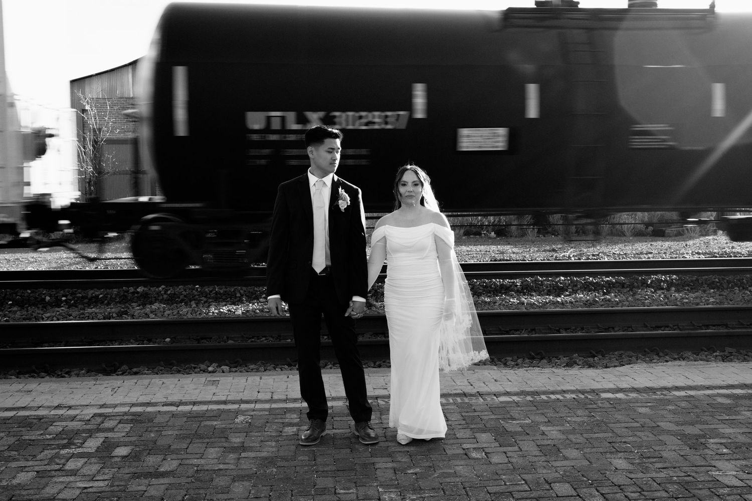 Bride and groom hold hands on train platform in classic black and white wedding photo in Flagstaff Arizona.