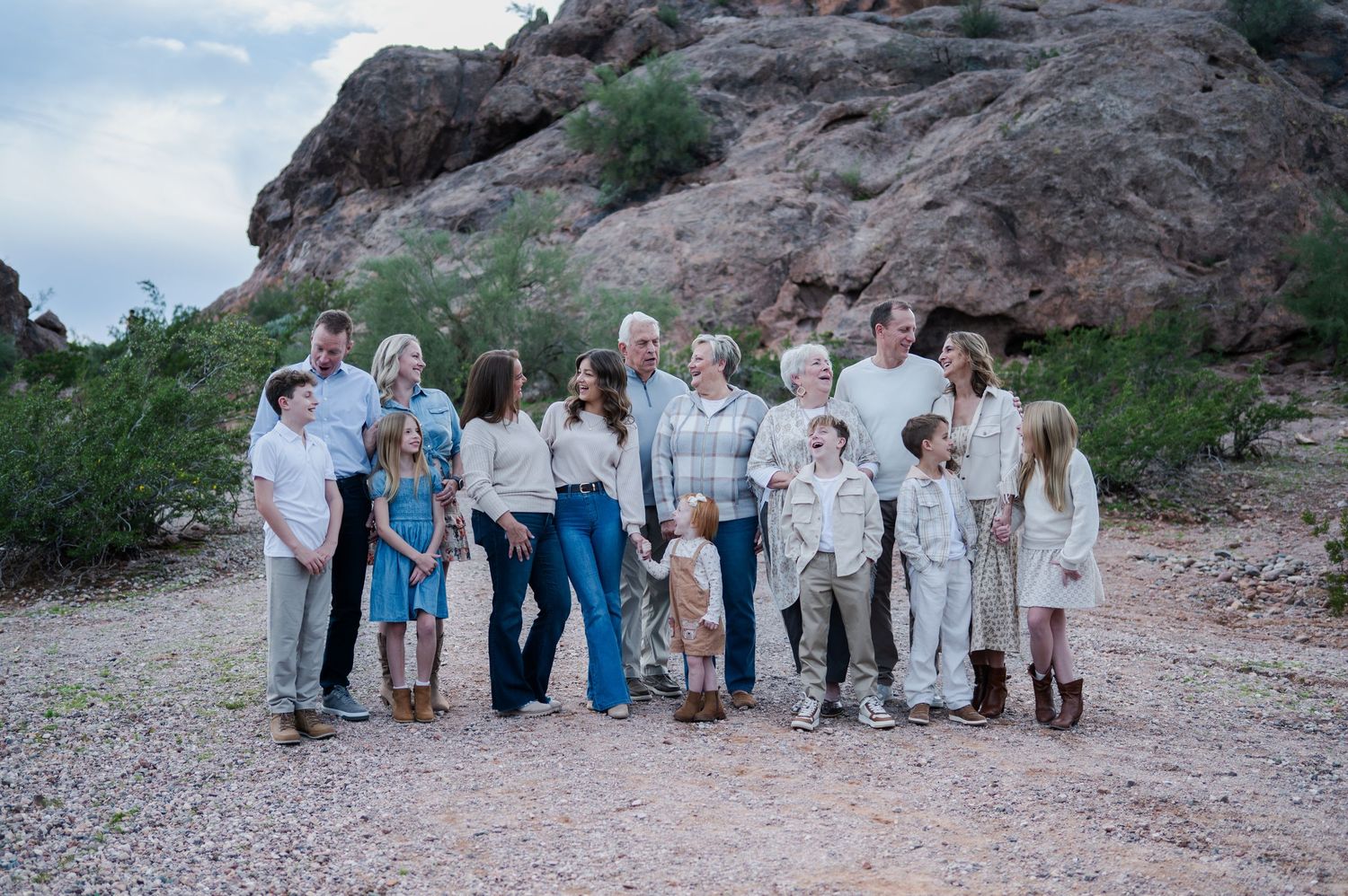 Large family group posing together outdoors near desert rock formations in casual neutral clothing.