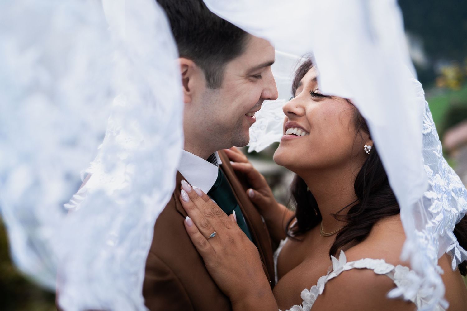 Bride and groom share an intimate moment under a lace veil, smiling at each other on their wedding day in Lauterbrunnen Switzerland.