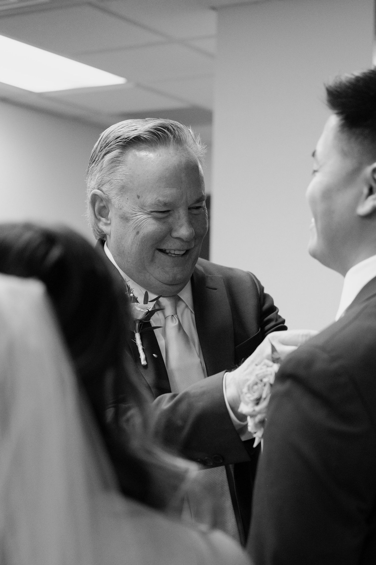 Older gentleman smiles warmly while greeting newlyweds in black and white candid wedding photo at the Flagstaff courthouse in Arizona.