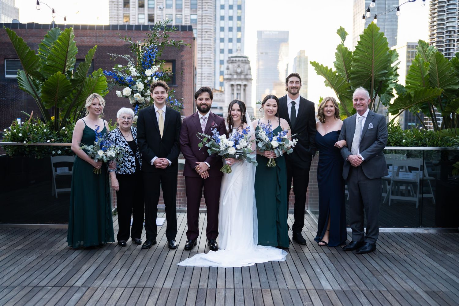 Wedding party group portrait on rooftop with city skyline, blue and white floral bouquets at The Pendry Hotel in Chicago Illinois.