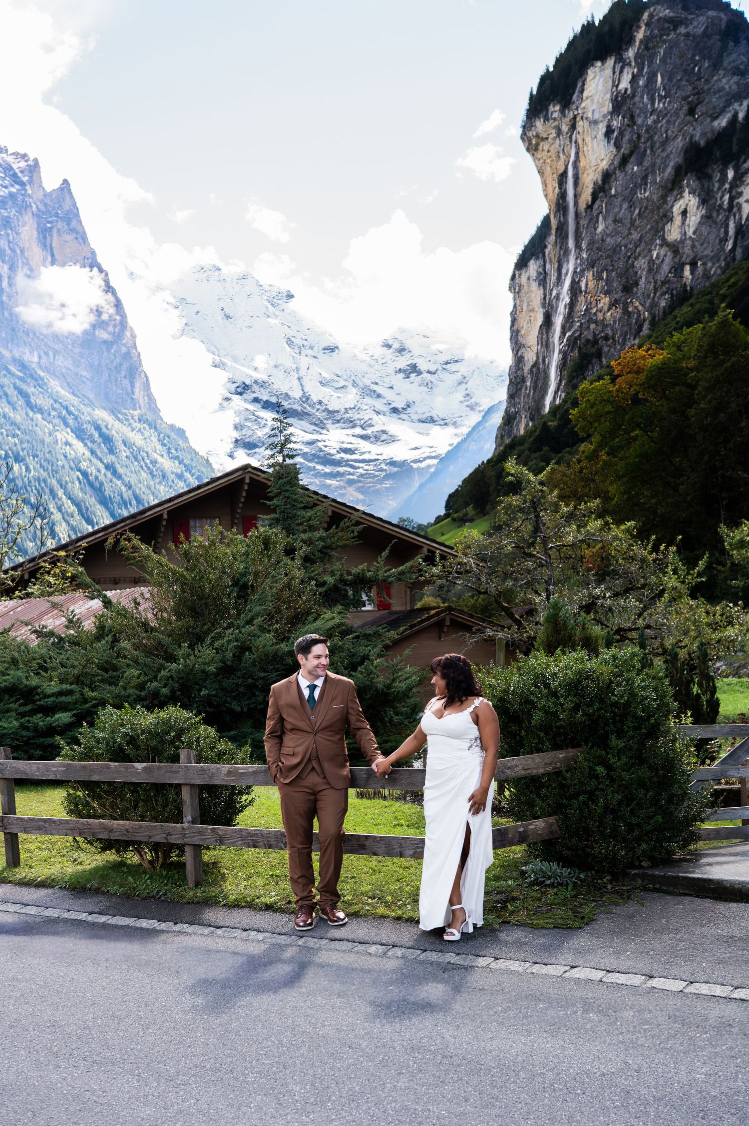 Couple holds hands on alpine street in Lauterbrunnen Switzerland with dramatic mountain cliffs and chalet backdrop in Lauterbrunnen Swiss