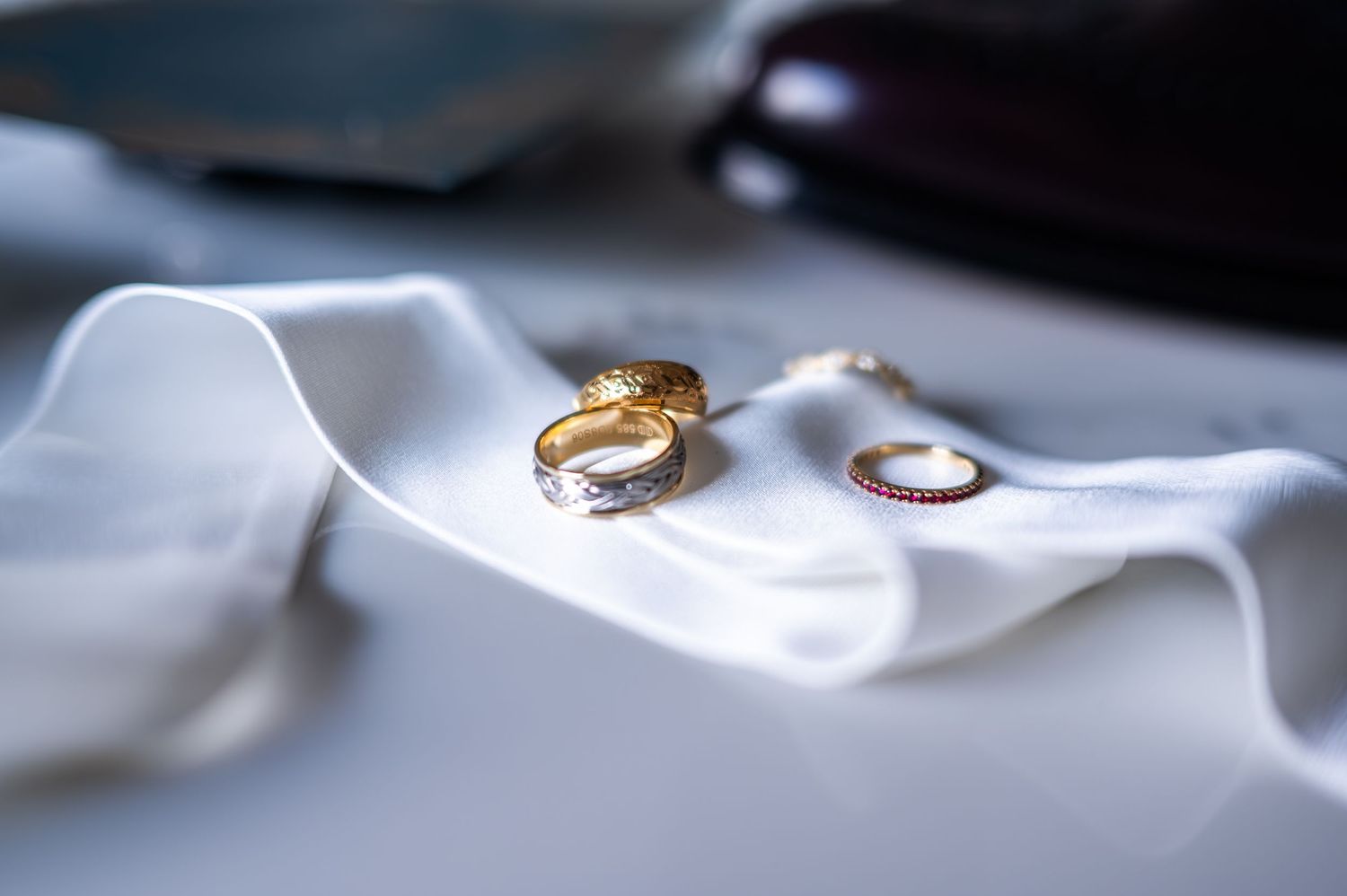 Gold and silver wedding rings displayed on white fabric with delicate jewelry details at The Pendry Hotel in Chicago Illinois.
