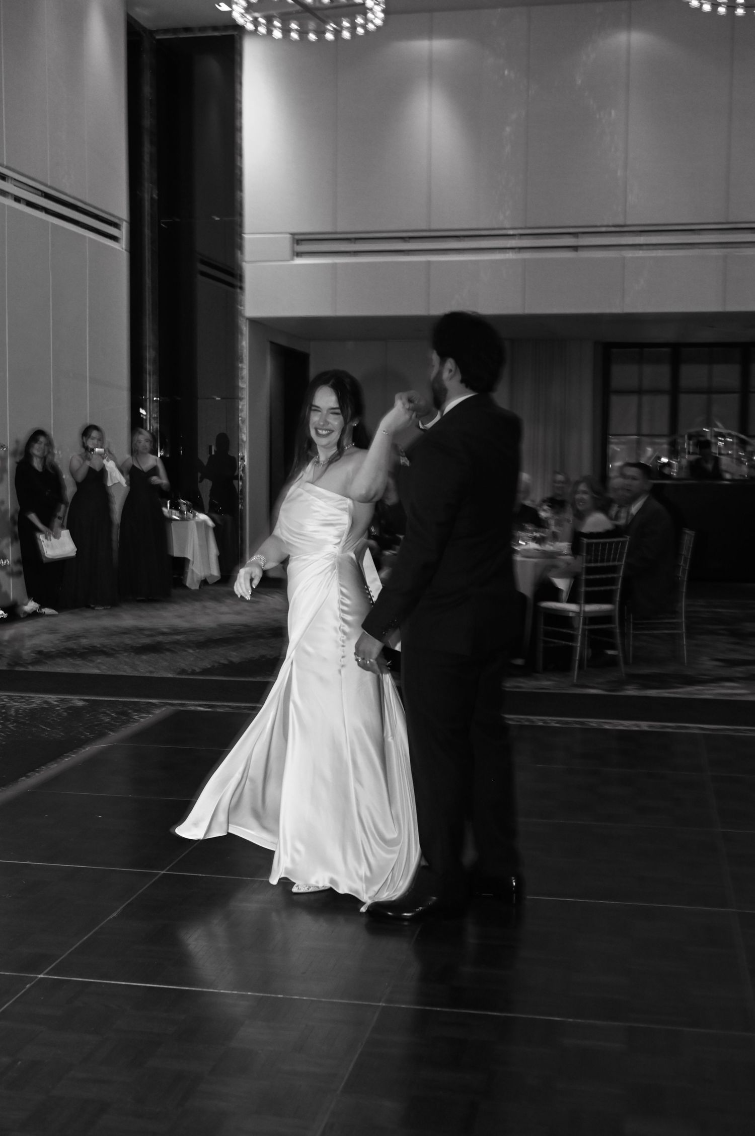 Bride and groom share their first dance in a grand ballroom in black and white wedding photo  at The Pendry Hotel in Chicago Illinois.