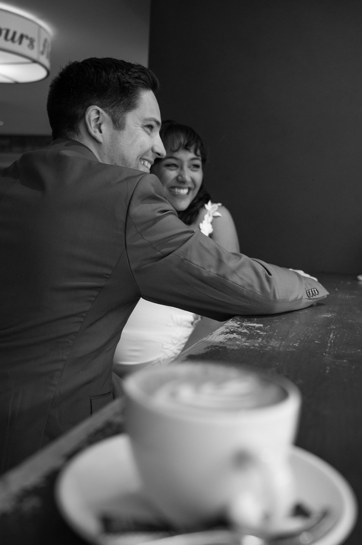 Couple sharing a romantic moment at a cafe with a latte art coffee cup in the foreground, black and white photo in Switzerland.