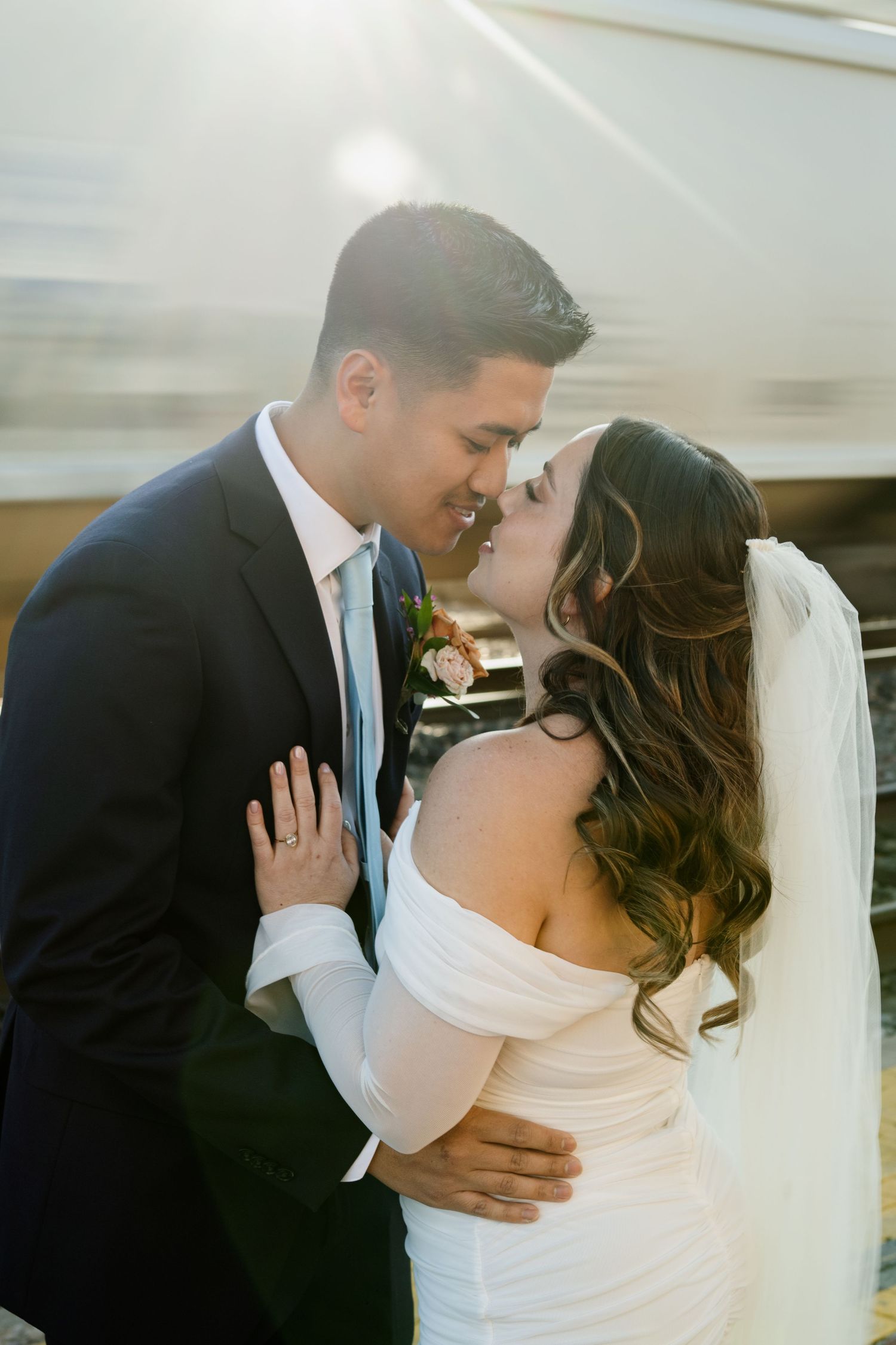 Bride and groom share a kiss bathed in golden light near a passing train in Flagstaff Arizona.