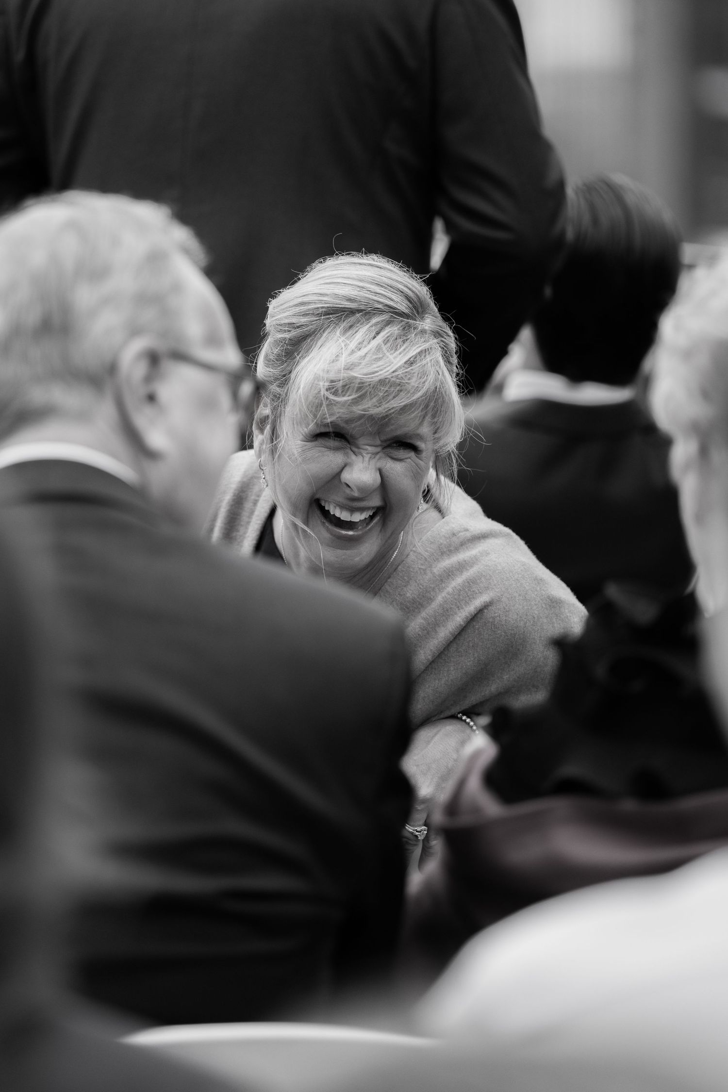 Joyful blonde woman laughing with guests at a wedding reception in black and white photo at The Pendry Hotel in Chicago Illinois.