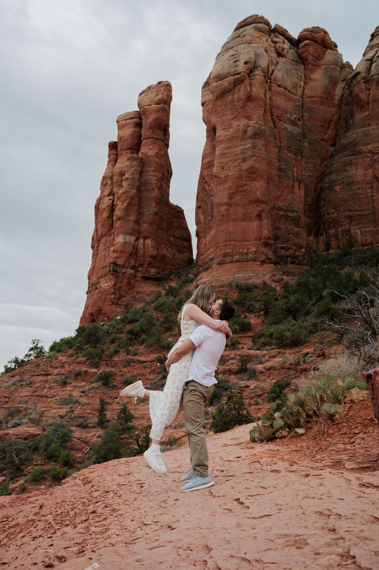 Couple embracing at red rock formations in Sedona, Arizona during an outdoor engagement photo session.
