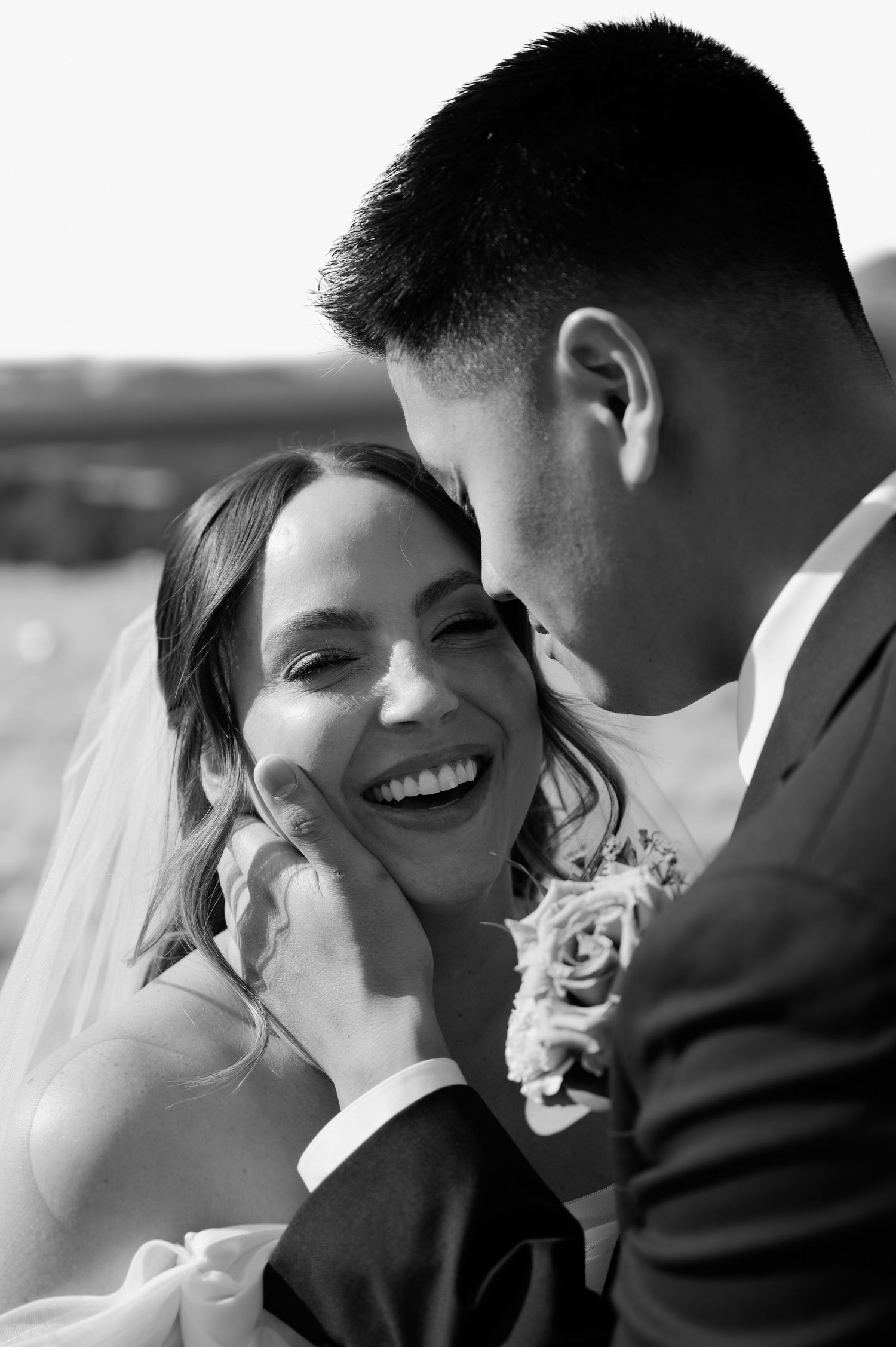 Groom tenderly cups brides face as she smiles in intimate black and white wedding portrait in Flagstaff Arizona.