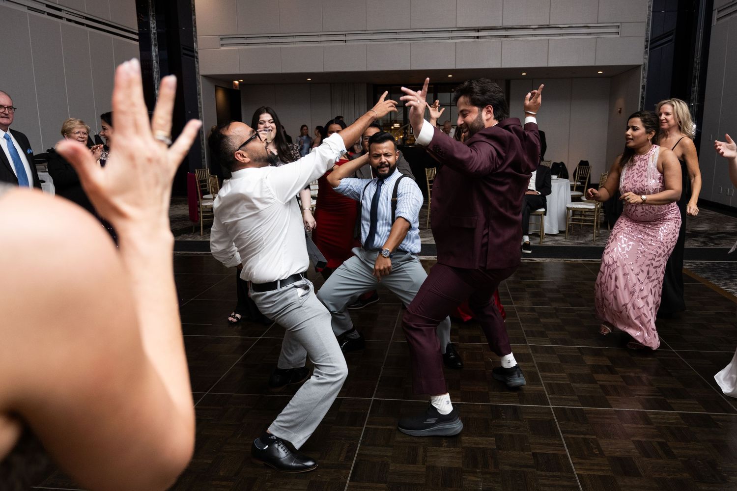 Energetic wedding guests dance and celebrate on the reception dance floor in festive attire at The Pendry Hotel in Chicago Illinois.