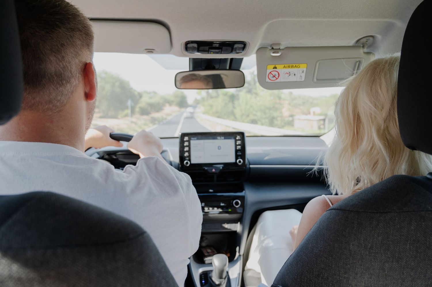 Candid rear view of bride and groom driving together in car on their wedding day in Tuscany Italy.