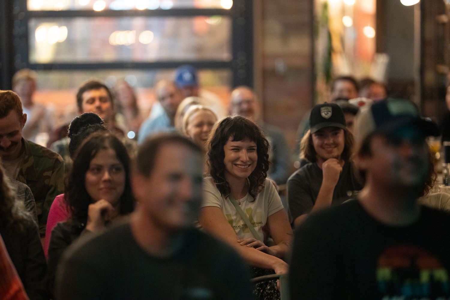 Diverse crowd of smiling people enjoying a live comedy show at a venue.