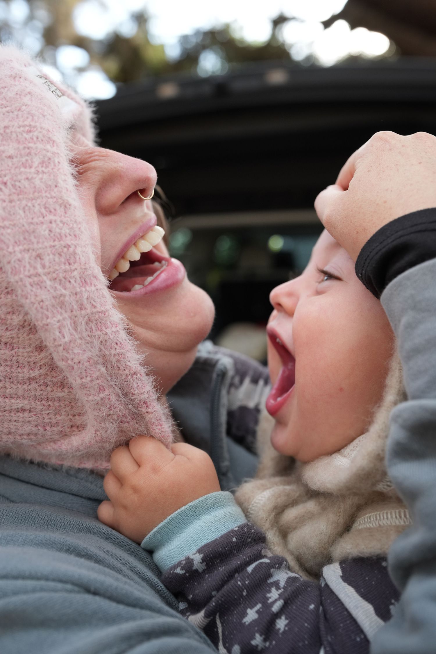 Woman and toddler both laughing with mouths open wide in a joyful moment.