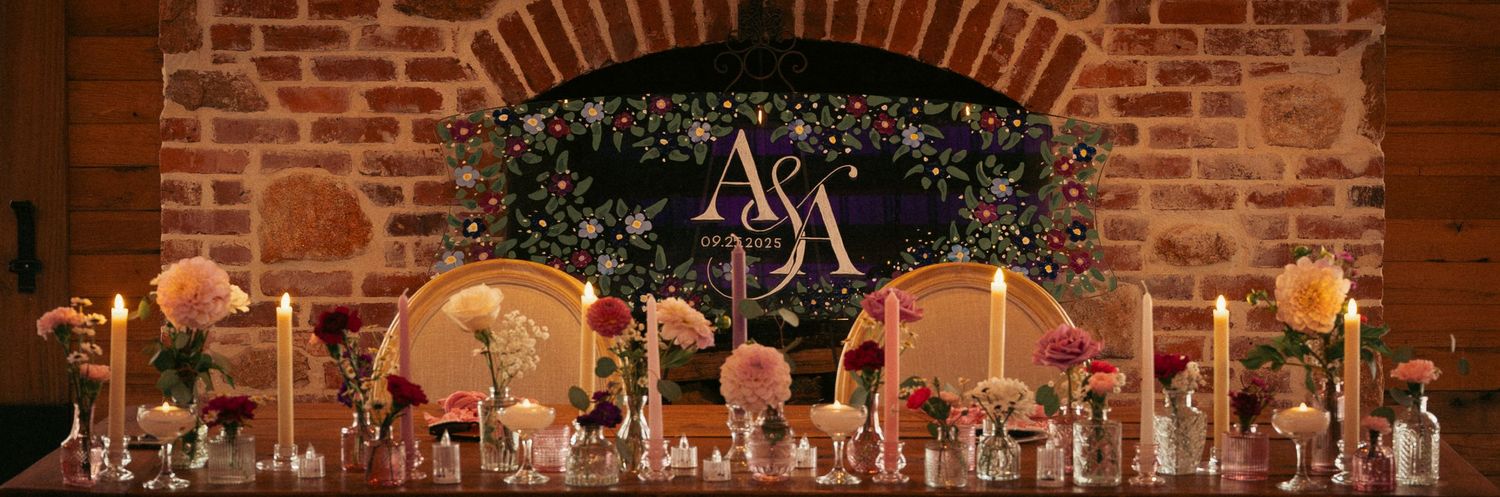 Elegant wedding reception table with floral arrangements beneath monogram backdrop.