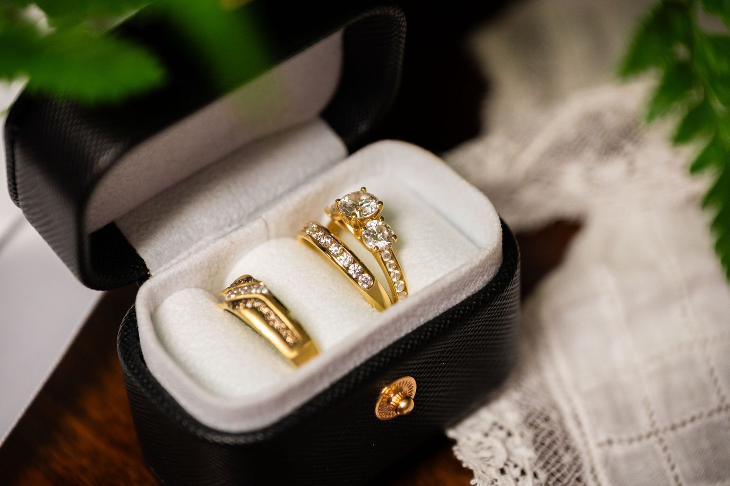 Two gold diamond wedding rings displayed in a black velvet jewelry box, perfect for an elegant bridal set.