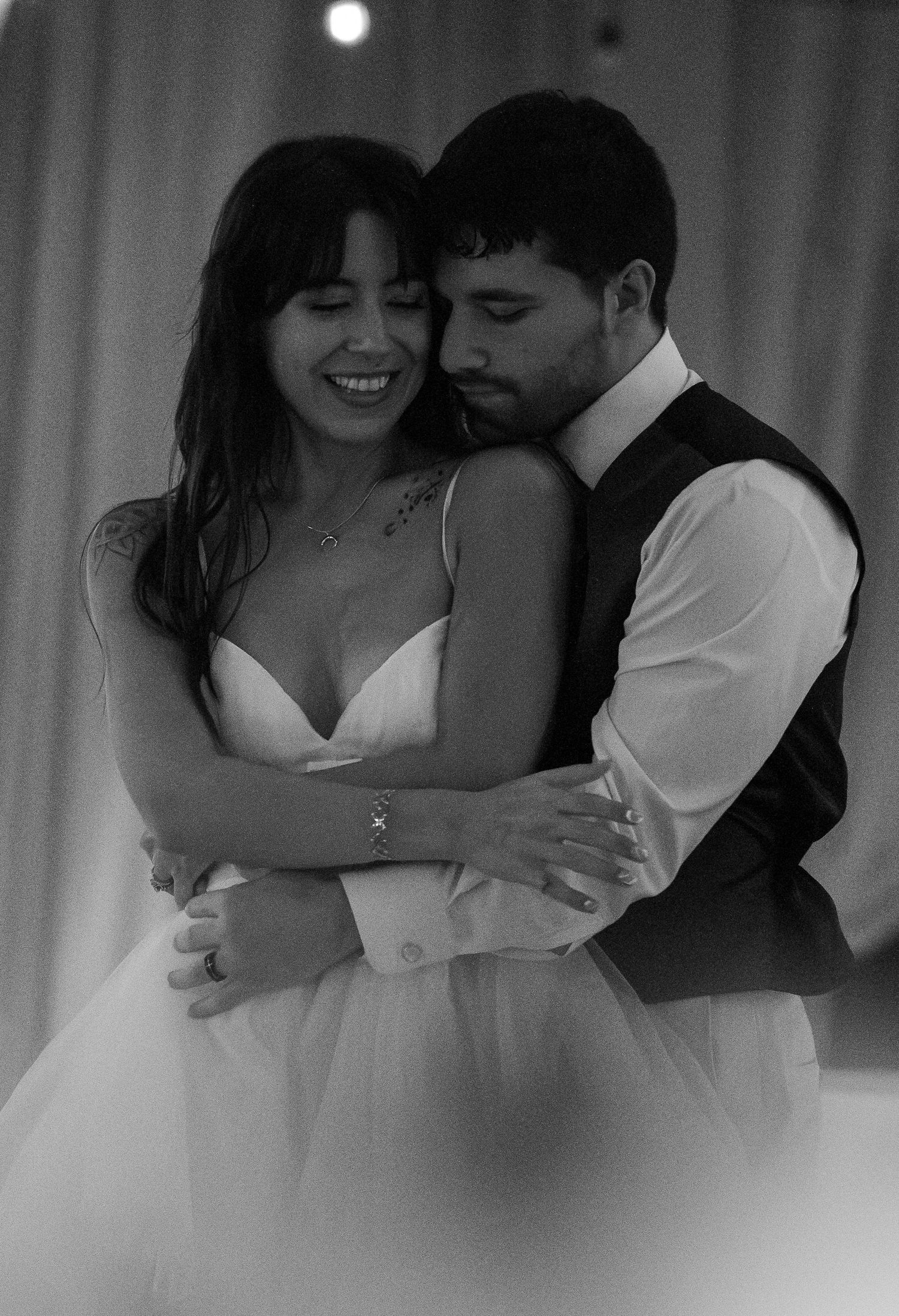 Black and white photo of a couple sharing a romantic first dance embrace at their wedding ceremony.
