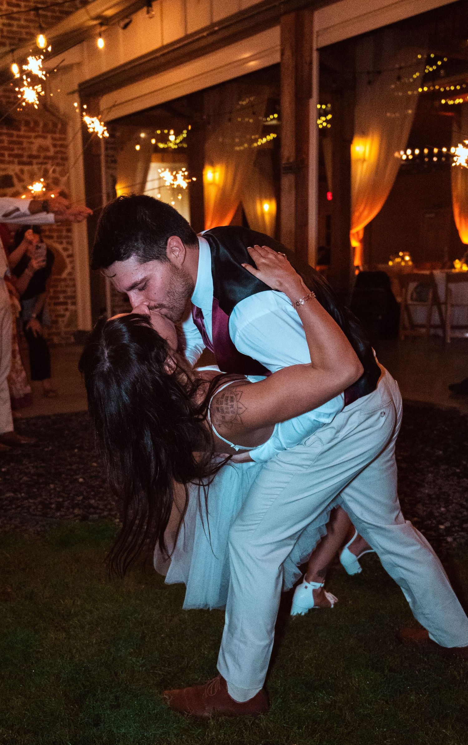 Bride and groom sharing a romantic dip kiss on the dance floor at their outdoor wedding reception.