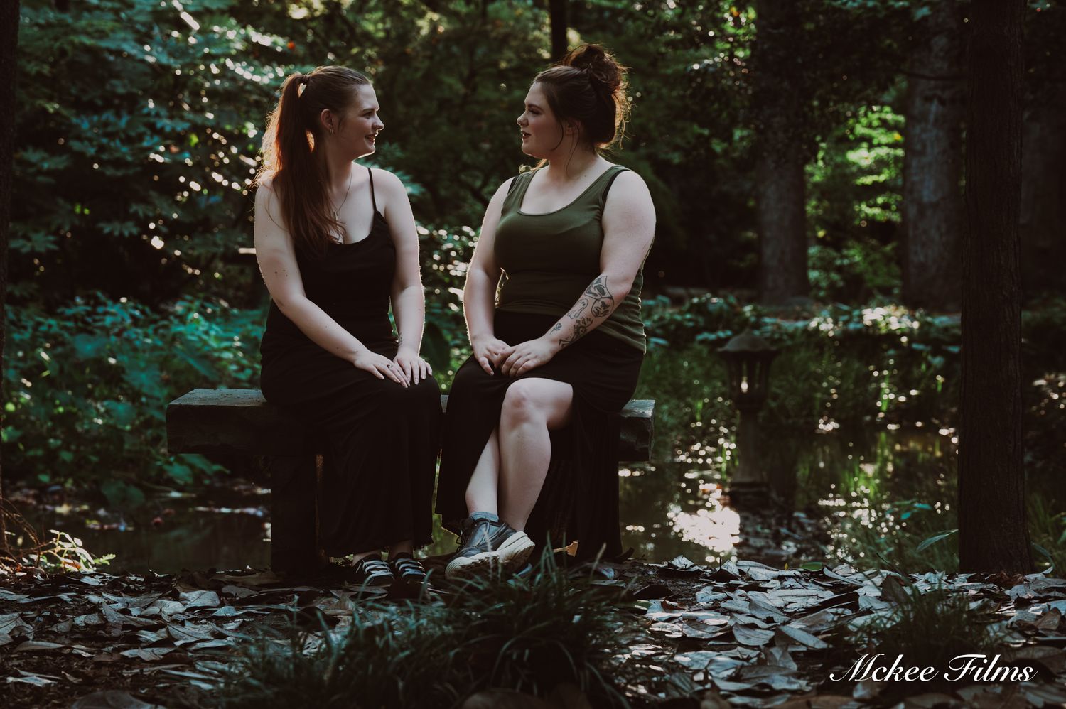 Two women laughing together in forest setting during outdoor portrait session.