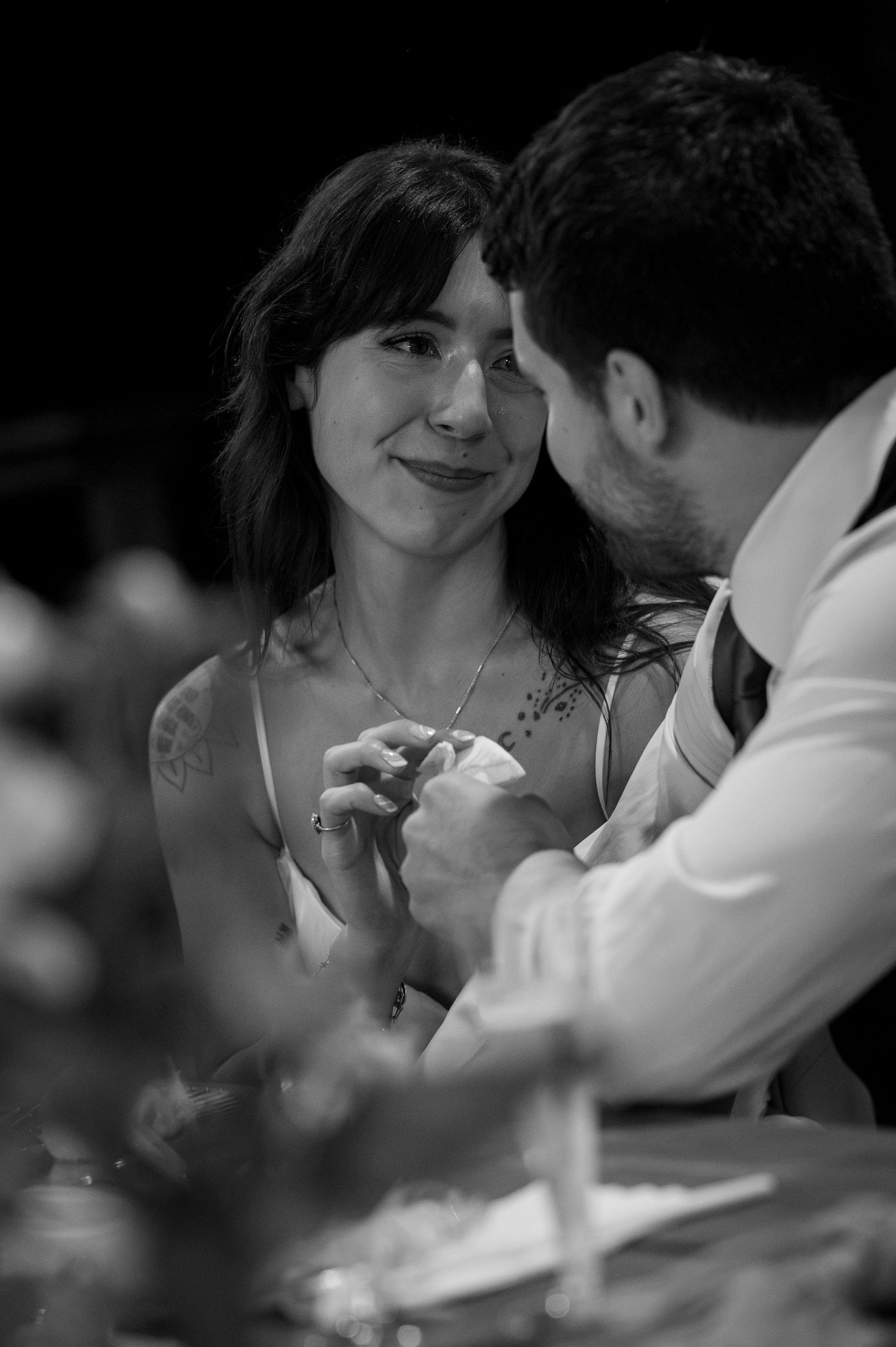 Black and white photo of a smiling bride and groom sharing an intimate moment at their wedding reception.
