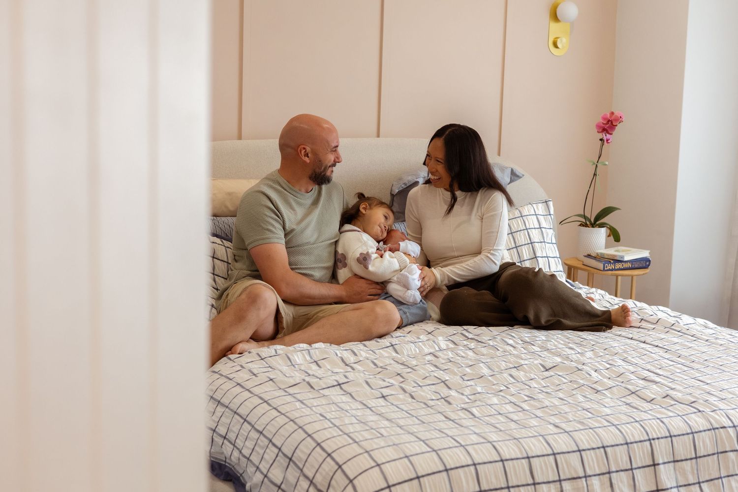 Parents cuddling their newborn during an in-home lifestyle photography session in Perth.