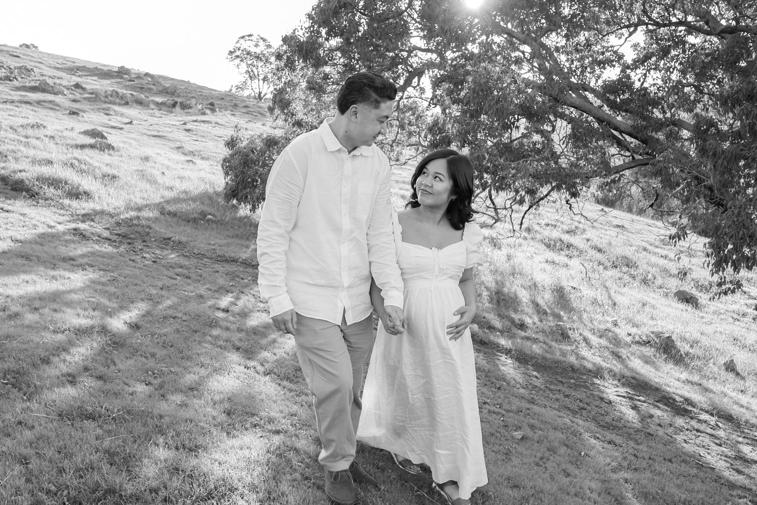 Couple embracing while expecting their first baby during a sunset maternity session.
