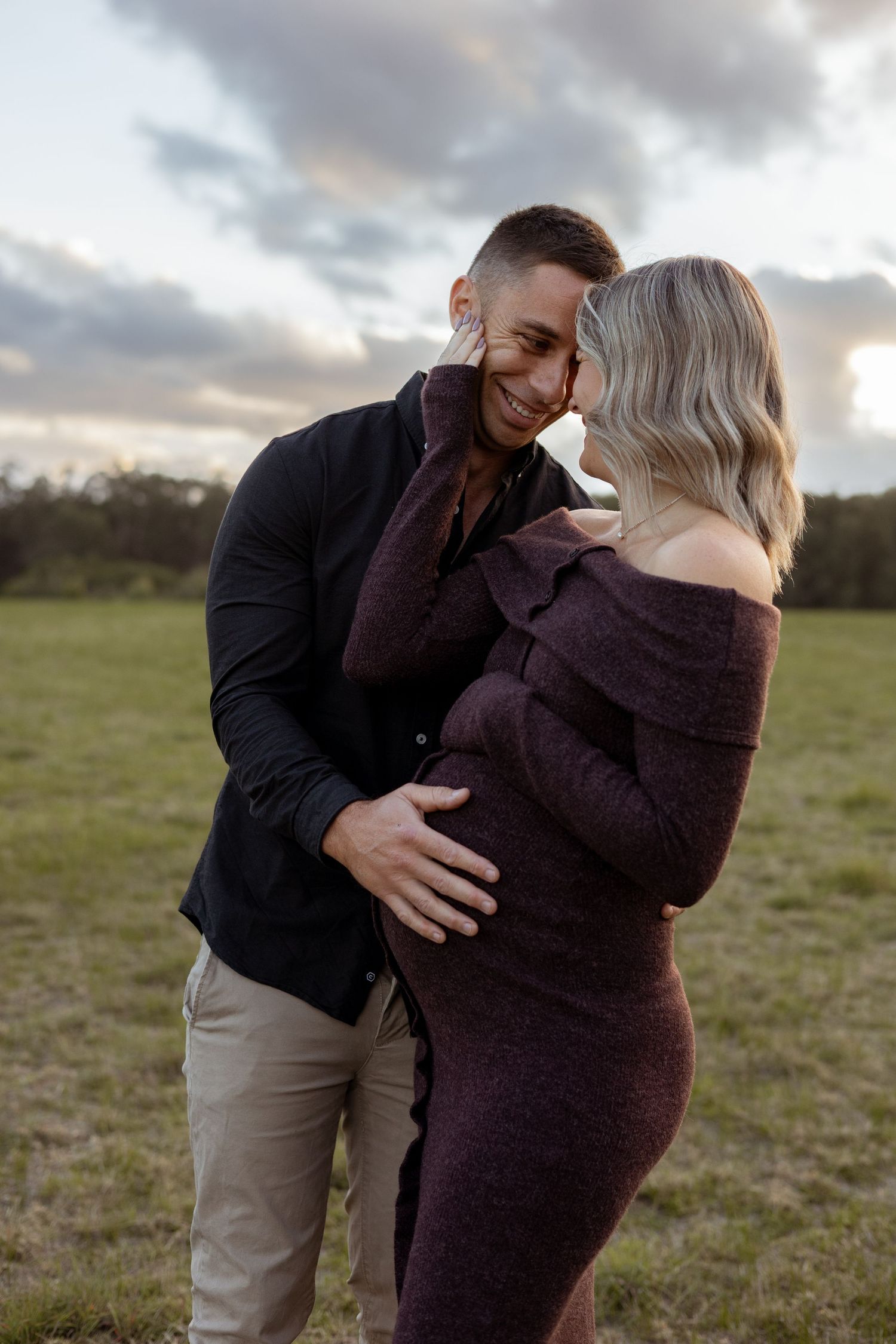 Couple embracing while expecting their first baby during a sunset maternity session.