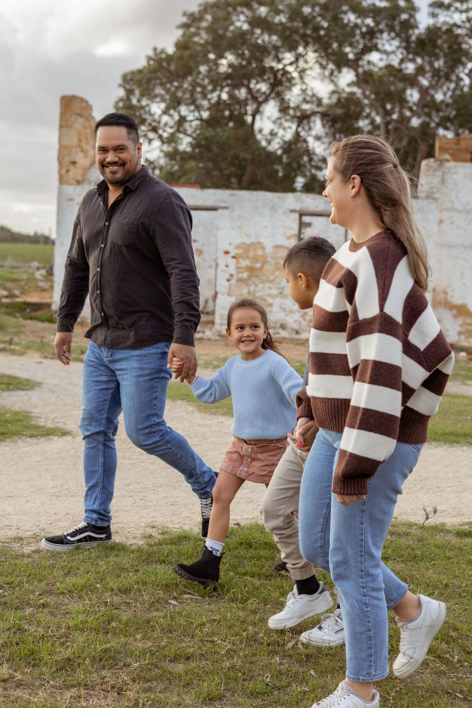 Young family walking hand in hand through a Perth nature reserve at golden hour.