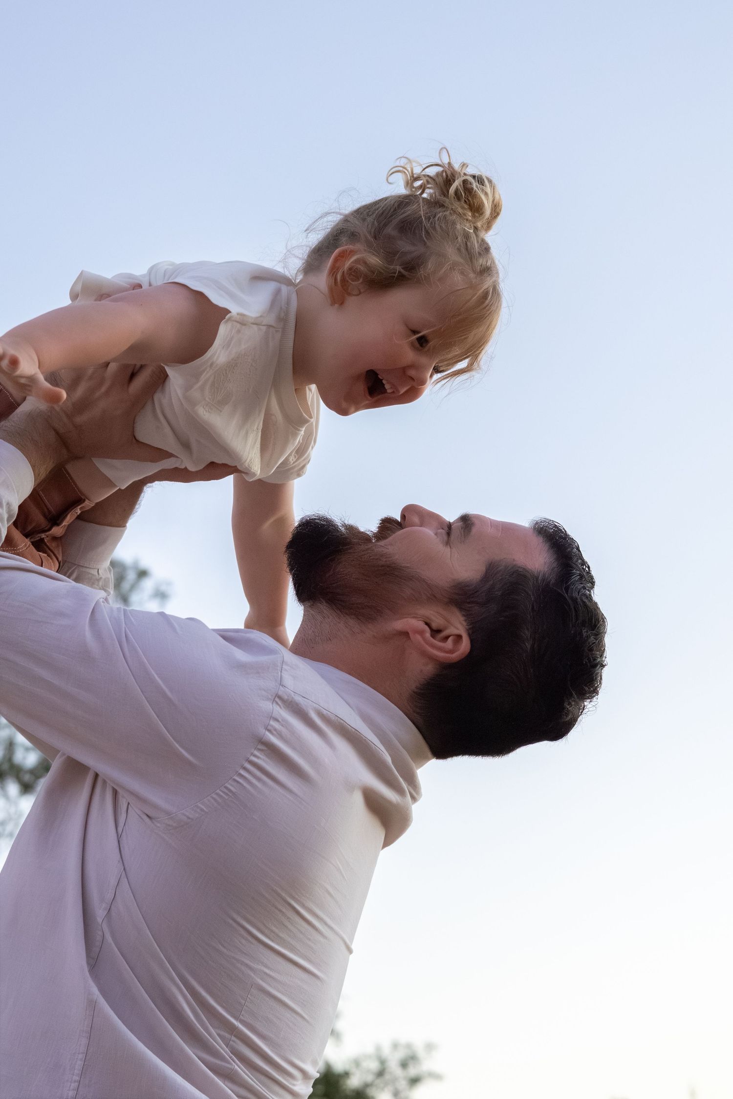 Dad lifting his toddler into the air during a lifestyle family session in Perth.