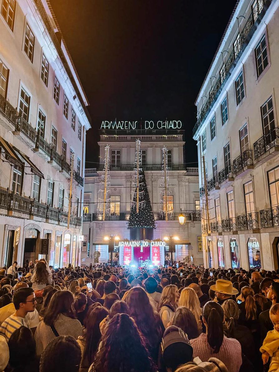 Crowd gathered at night in Lisbon's Chiado square for a Christmas tree lighting event outside Armazens do Chiado.