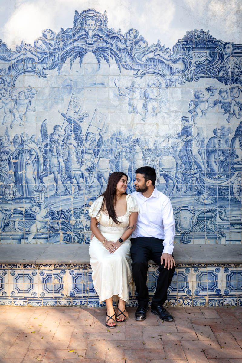 Couple sitting together in front of ornate blue and white Portuguese azulejo tile wall mural.