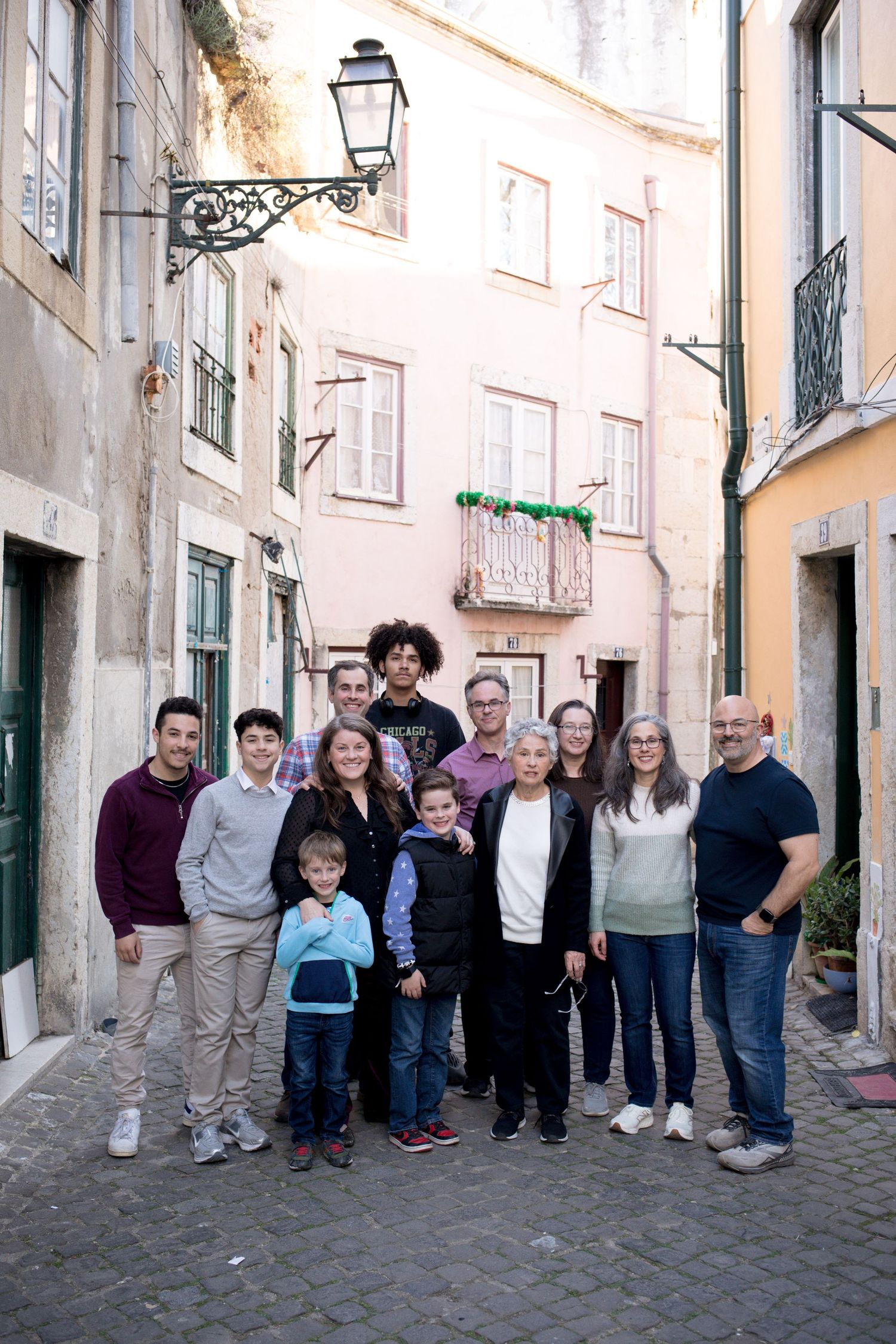 Large multigenerational family group portrait on a cobblestone street in Lisbon, Portugal.
