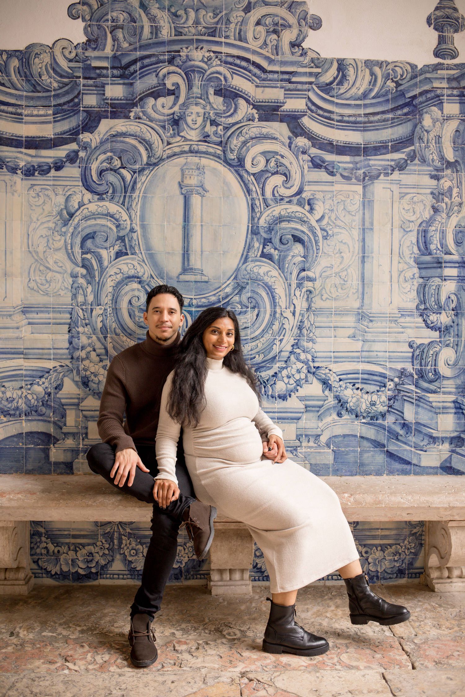 Couple posing in front of ornate blue and white Portuguese azulejo tile wall.