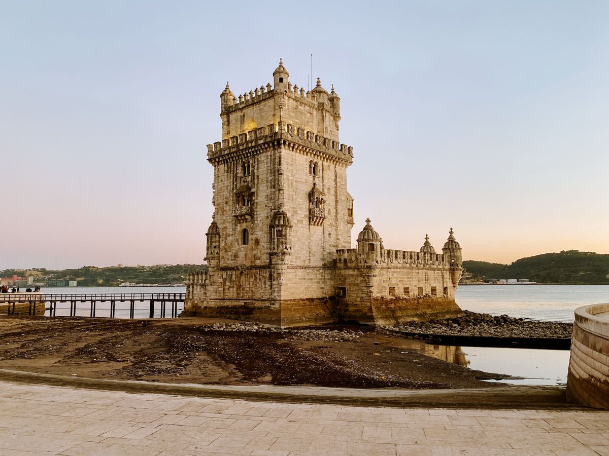 Historic Belem Tower standing on the Tagus River in Lisbon, Portugal, at golden hour with calm waters.