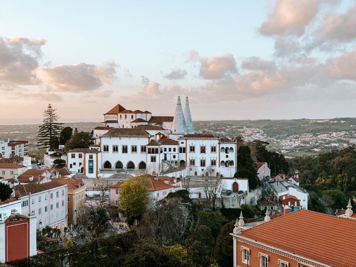 Aerial view of Sintra, Portugal, featuring the National Palace and colorful rooftops at sunset.