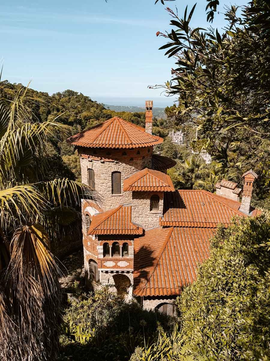 Aerial view of a historic stone villa with terracotta roof tiles nestled among lush green trees.