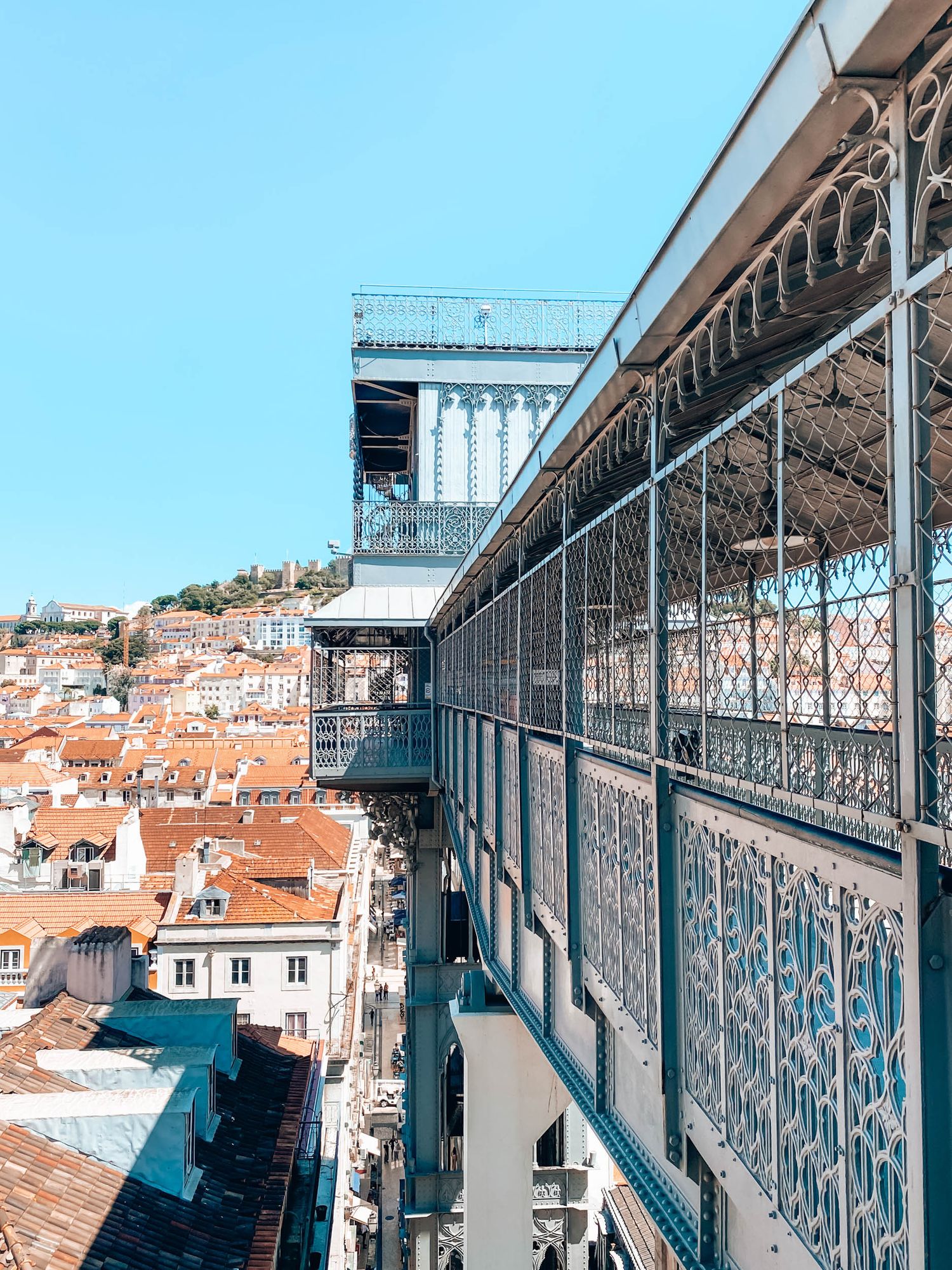 Aerial view of the Santa Justa Lift in Lisbon, Portugal, with ornate ironwork and terracotta rooftops below.