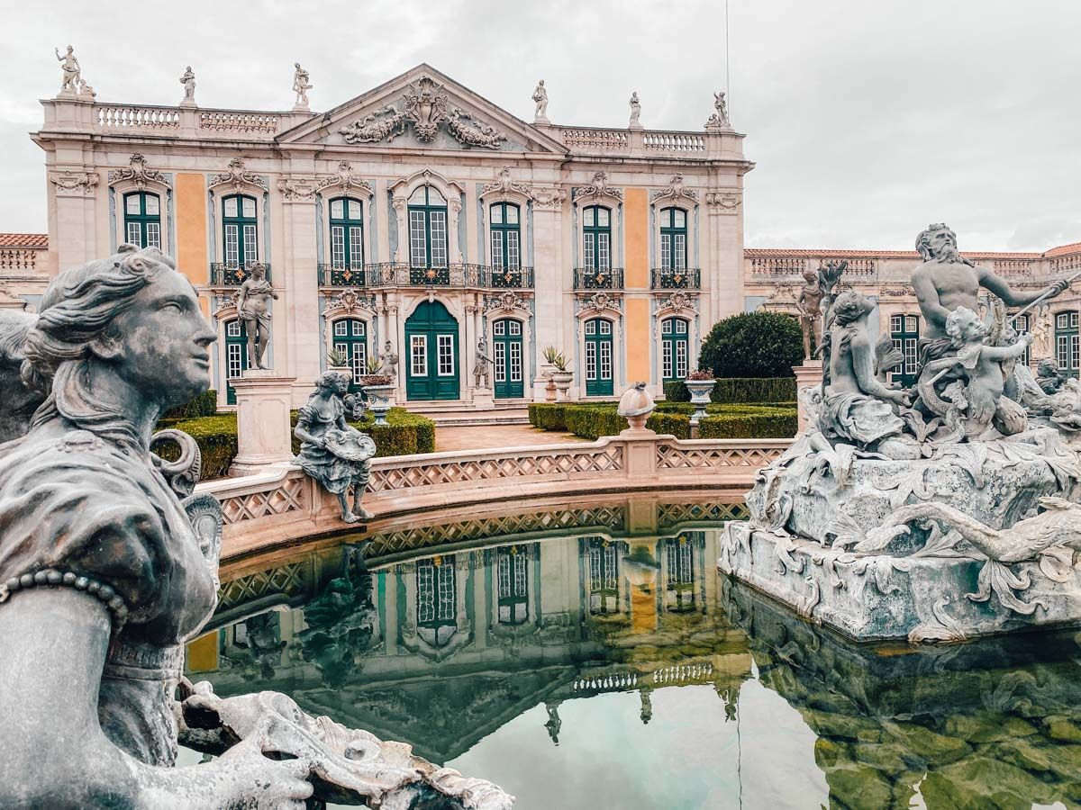 Baroque palace with ornate stone fountains and reflecting pool in Queluz, Portugal.