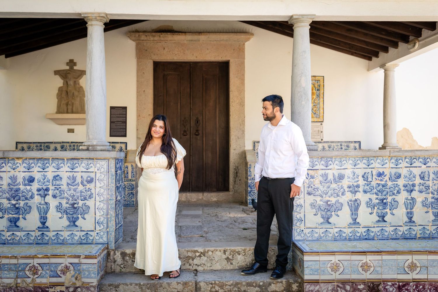 Proposal in Cascais with a couple posing by historic blue azulejo tiles and stone columns after their engagement.