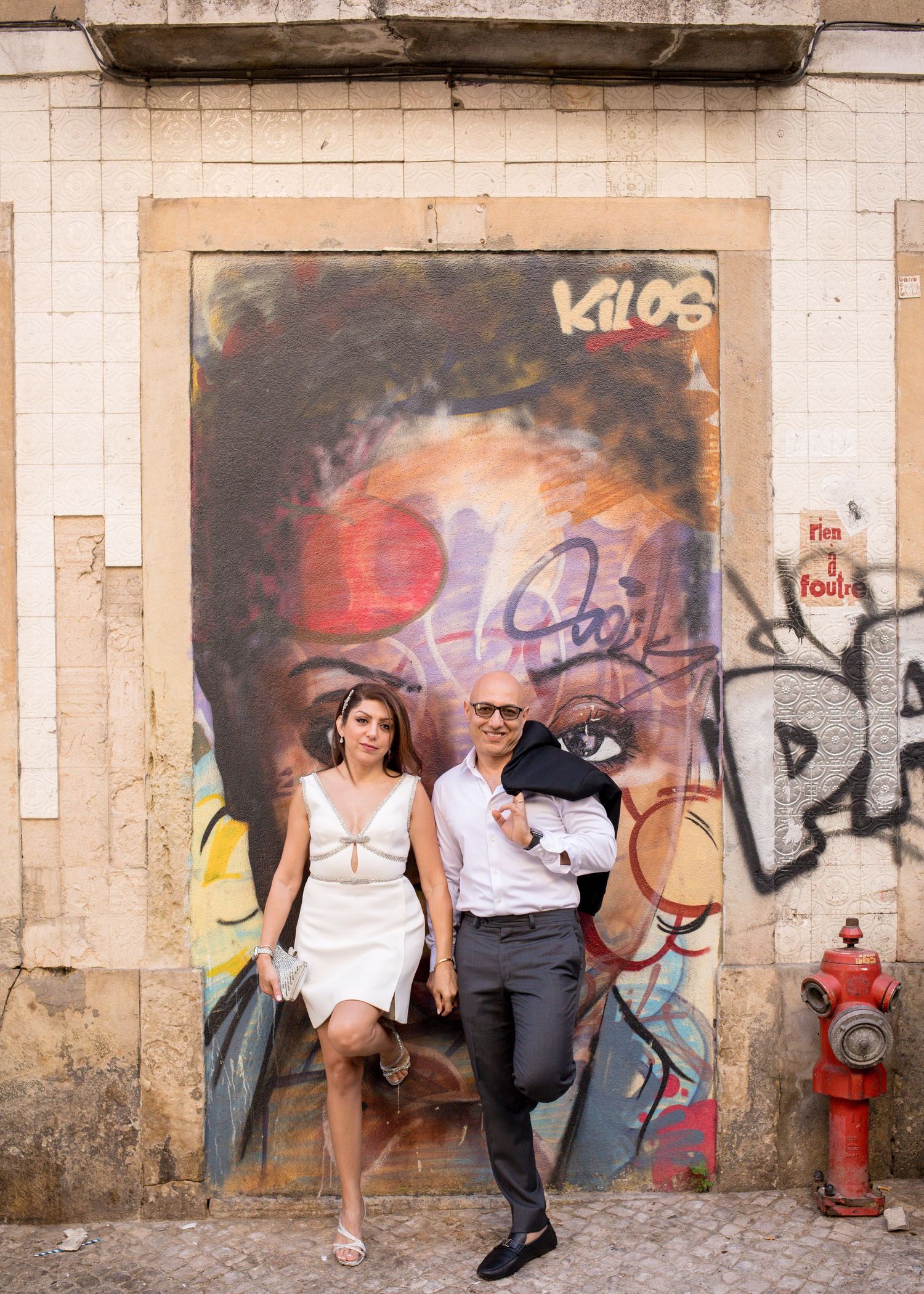 Couple posing hand in hand by colourful Lisbon street art during a Lisbon wedding anniversary photoshoot.