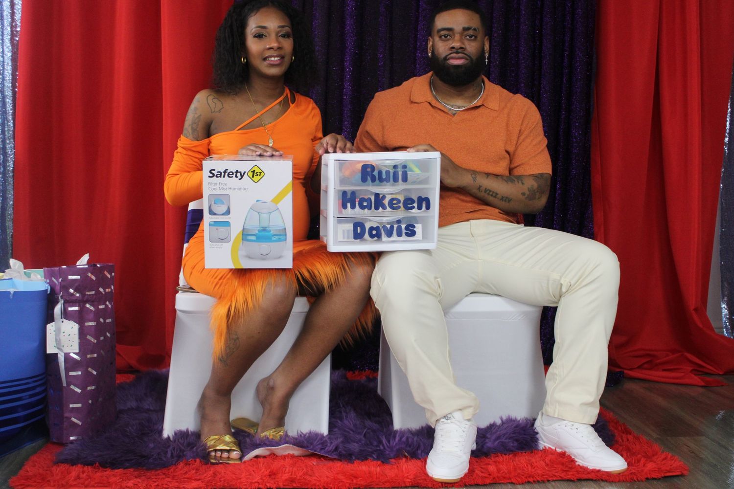 Couple posing with baby shower gifts and name sign for Ruli Hakeem Davis.