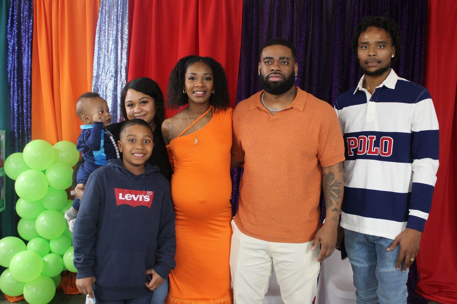 Family of five posing together in front of colorful balloon decorations at a party.