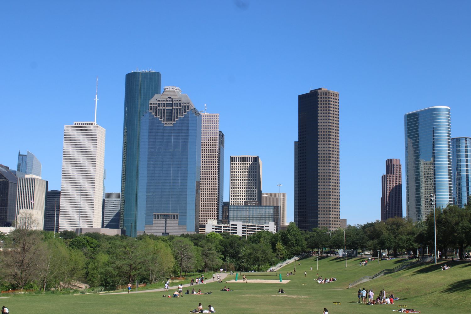 Houston skyline with skyscrapers viewed from a green park on a sunny day with people relaxing on the grass.