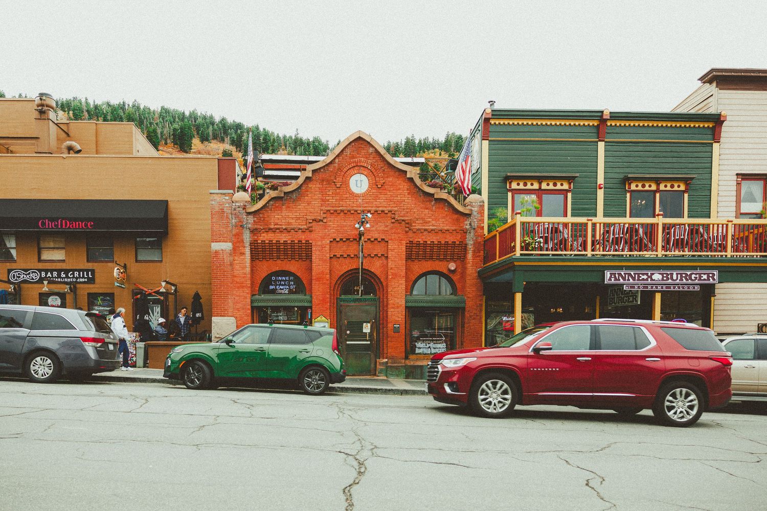Colorful historic storefronts with parked cars on a small town main street.